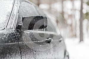 Icicles hanging from car side mirror in freezing rain weather conditions. Vehicle covered in freezing rain ice.