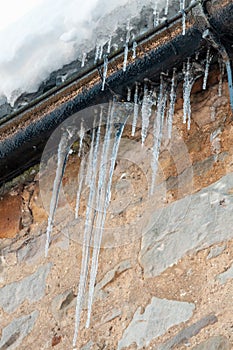 Icicles hanging from guttering on a stone wall