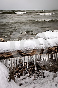 Icicles hanging from an old log on a rocky beach