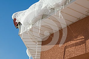 The icicles hanging from the rim of the roof. The spring background of melting ice and snow in the sunny day