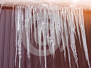 Icicles hanging from the roof on the background
