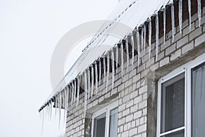 Icicles hanging from the roof of a village house in winter.