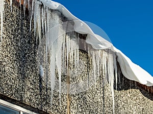 Icicles hanging from rooftop covered with a lot of snow