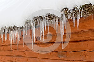 Icicles hanging from a snowy roof on a barn