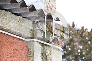 Icicles on the roof. Insecure roof. Freezing water in the icicle.