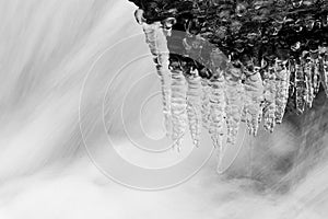 Icicles on stone and flowing water under