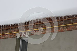 Icicles under edge of roof covered with snow