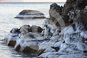 Icing on the coastal rocks. New winter ice frost on the sea shoreline.
