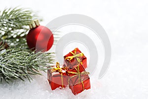 Icing pine branch with red matt christmas ball and three christmas red gift box with yellow bow on snow photo