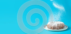 Icing sugar falling on bundt cake, blue background