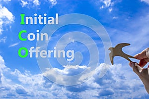 ICO initial coin offering symbol. Concept words ICO initial coin offering on beautiful blue sky clouds background. Wooden bird.