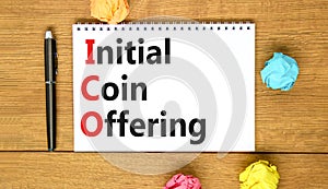 ICO initial coin offering symbol. Concept words ICO initial coin offering on beautiful white note. Beautiful wooden table wooden