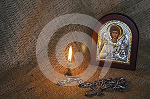 Icon of the Archangel Michael with silver and gilding, a pectoral cross and a burning candle