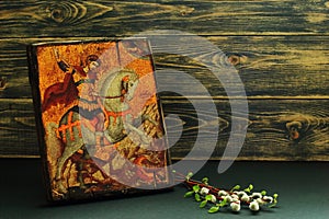 Icon of St. George the Victorious replica and willow and birch branches on dark wooden background. Symbolic concept â€” faith,