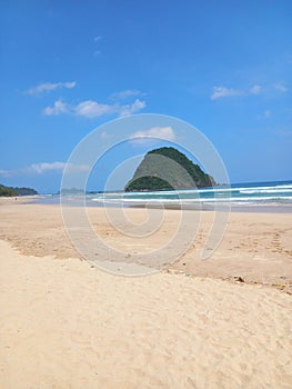 Iconic Banyuwangi (indonesia) Beach called Pantai Pulau Merah with blue sky and a uninhabited island. taken at May, 2023