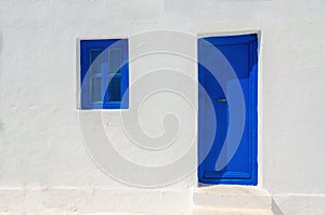 Iconic blue wooden door and window against clear white wall.
