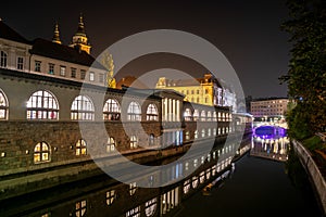 Iconic building of the central market in Ljubljana illuminated at night, the bridge of Preseren sqare in the background photo