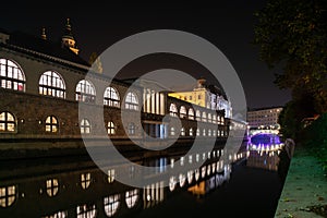 Iconic building of the central market in Ljubljana illuminated at night, the bridge of Preseren sqare in the background photo