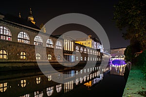 Iconic building of the central market in Ljubljana illuminated at night, the bridge of Preseren sqare in the background photo