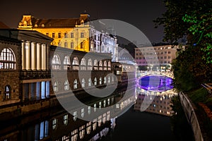 Iconic building of the central market in Ljubljana illuminated at night, the bridge of Preseren sqare in the background photo