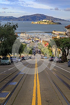 Iconic cable car tracks atop Hyde Street, with the famous Alcatraz Island in background in San Francisco, California USA