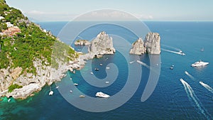 The iconic Faraglioni rocks emerge from Capri's azure sea. Towering sea stacks, luxury vessels navigate the serene