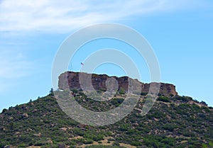 Iconic landmark butte Castle Rock in its namesake city in Colorado with American flag waving in the wind