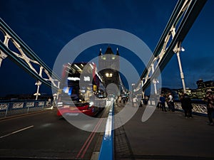 Iconic red double-decker bus on illuminated famous Tower Bridge Thames river in London England UK Great Britain at night