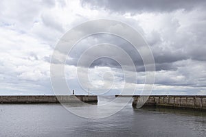 Iconic striped Seaham lighthouse on pier with clouds and sea walls