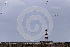 Iconic striped Seaham lighthouse on pier with clouds and sea walls