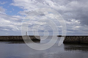 Iconic striped Seaham lighthouse on pier with clouds and sea walls