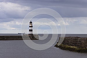 Iconic striped Seaham lighthouse on pier with clouds and sea walls