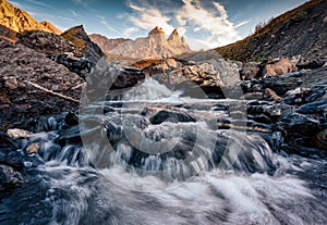 Iconic three peak mountain and waterfall flowing in the Aiguilles d Arves among the French Alps at Savoie, France