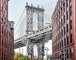 Iconic view of Manhattan Bridge from Washington Street. Red brick street buildings leading to the bridge at dusk. Brooklyn. NYC,