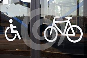 Icons for disabled person and bicycle on glass bus doors, close-up