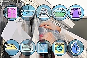 Icons and female worker taking clothes from garment conveyor at dry-cleaner`s, closeup