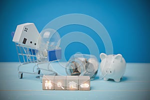 Icons people, magnifying glass, house, and money on wood blocks behind have a light bulb with a little wooden house on a blue