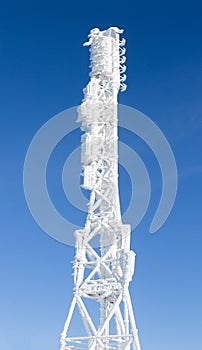Icy cellular base station antenna covered with snow. Cell site tower on moutain hill