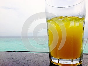 Icy cold orange juice in front of ocean tropical island holiday