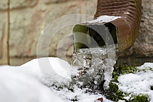 Icy gutter in a single-family house. Ice icicles in the drainage gutter