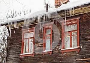 Icy, long icicles hang on the edge of the roof, winter or spring