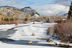 Icy river in winter sunshine with mountain backdrop. Winter in Wyoming