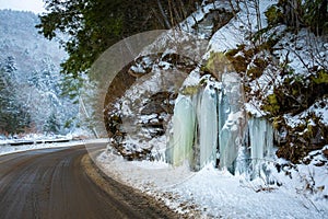 Icy road pavement with frozen ice along the side