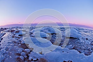 Icy seashore at sunset in the cold winter.