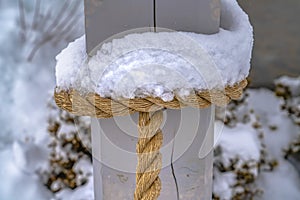 Icy snow on the rope tied to a wooden post
