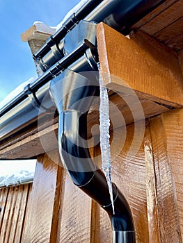 Icycles hanging from guttering on the side of a wooden house. Hovden, Norway, Feb 2023.