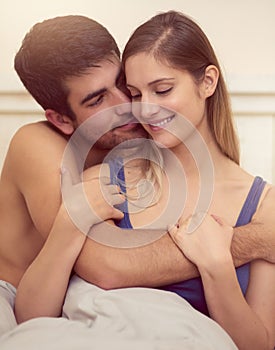 Id hug you all day if I could. a loving young couple sharing an intimate embrace while sitting in bed.