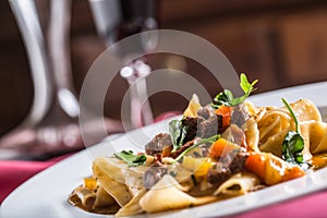 Idalian pasta pappardelle with beef ragout on white plate and re