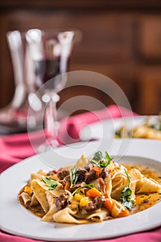 Idalian pasta pappardelle with beef ragout on white plate and re