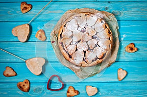 Idea for the celebration of Valentine`s Day: cherry pie with the decor the dough in the shape heart on wooden table.